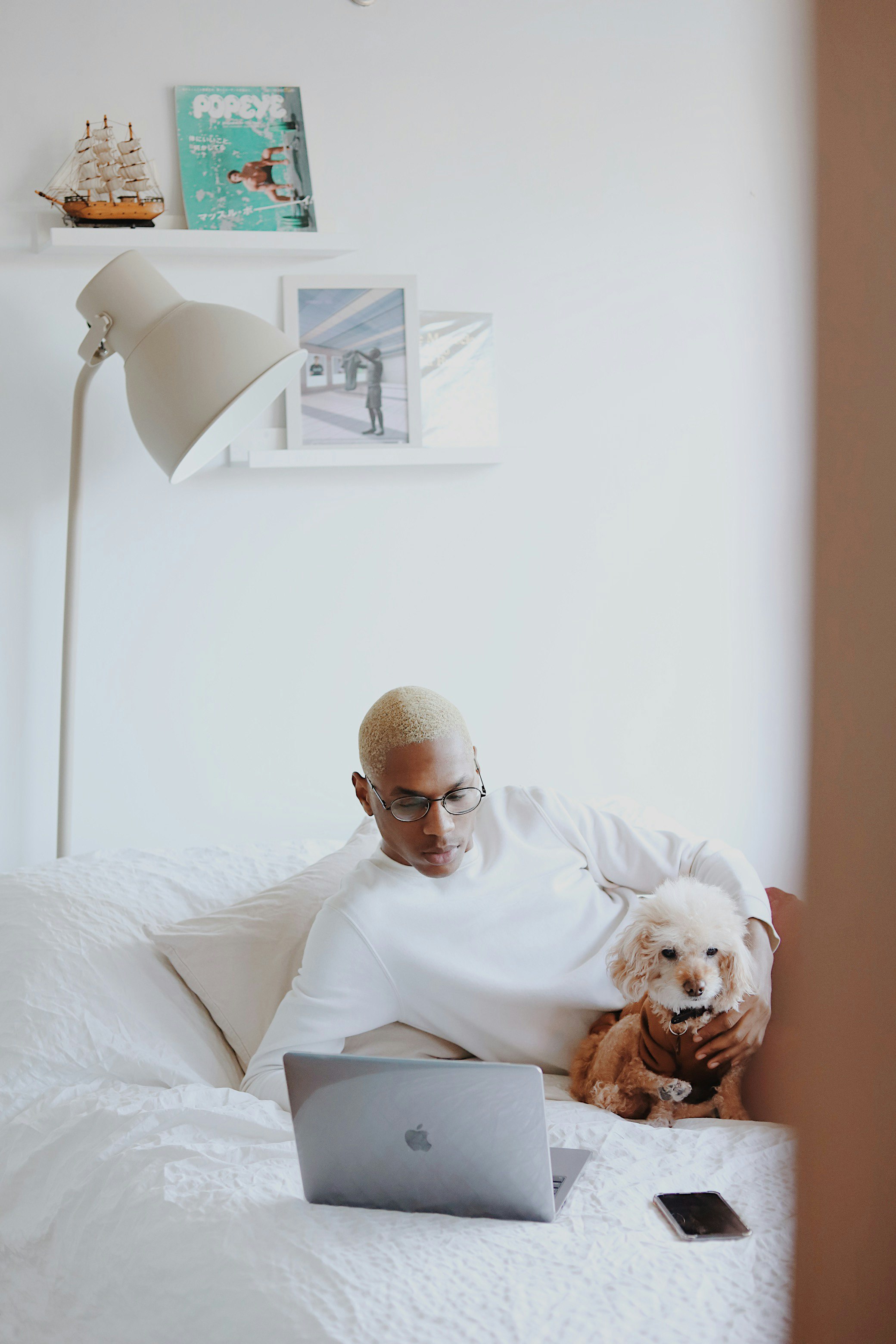 man in white shirt reading book on bed